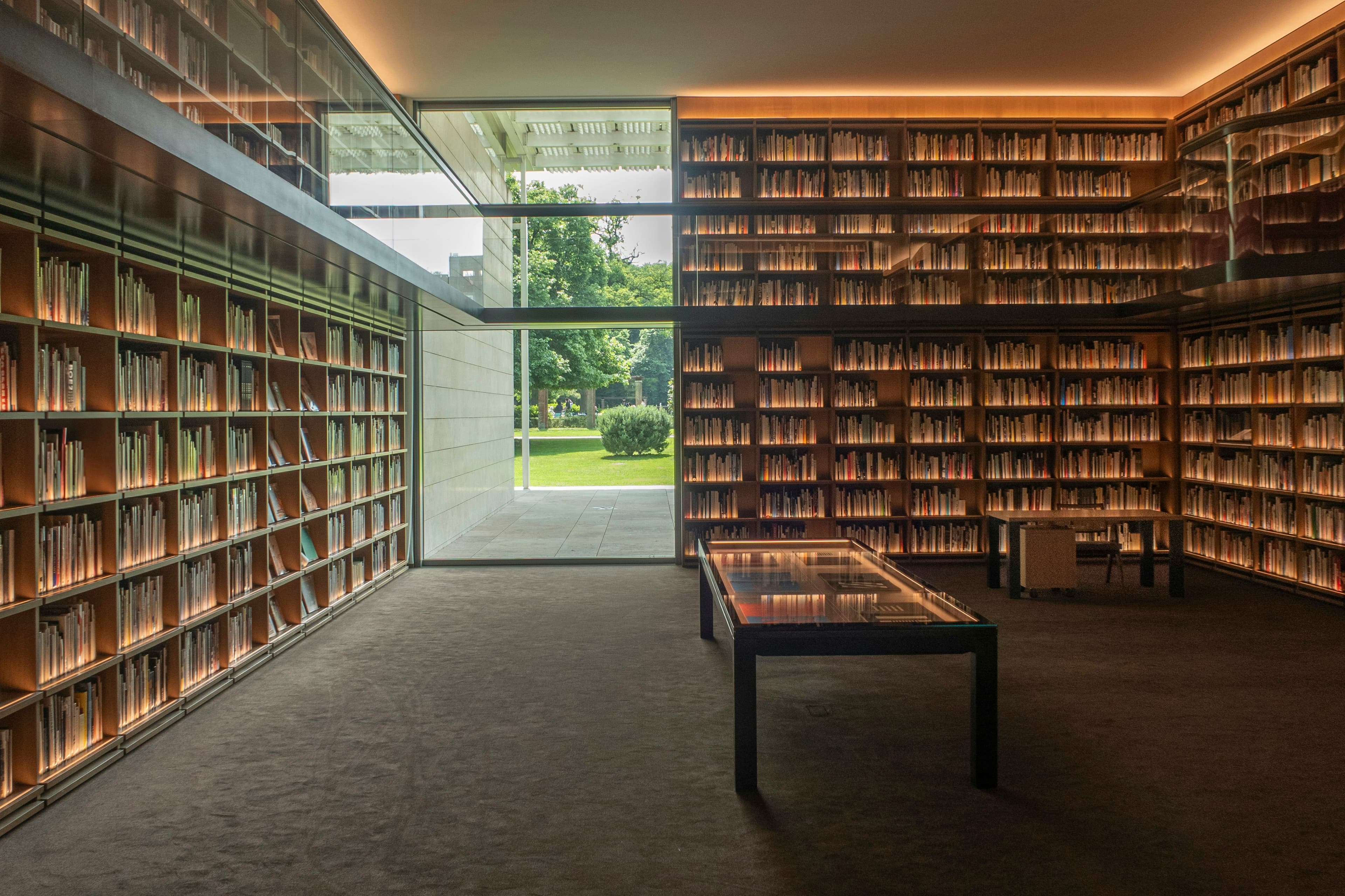 Biblioteca con scaffali a tutta altezza e una grande vetrata sul giardino